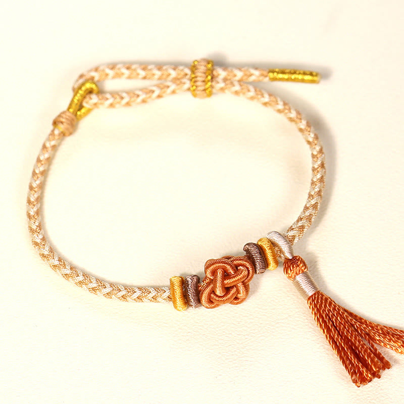 Bracelet de protection avec pompons et nœuds en fleurs de pêcher et Buddha Stones colorées