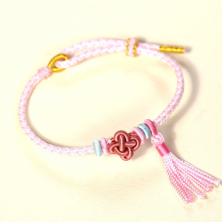 Bracelet de protection avec pompons et nœuds en fleurs de pêcher et Buddha Stones colorées