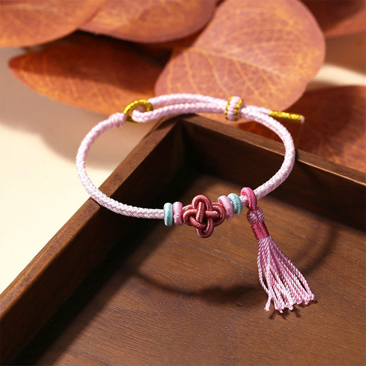 Bracelet de protection avec pompons et nœuds en fleurs de pêcher et Buddha Stones colorées