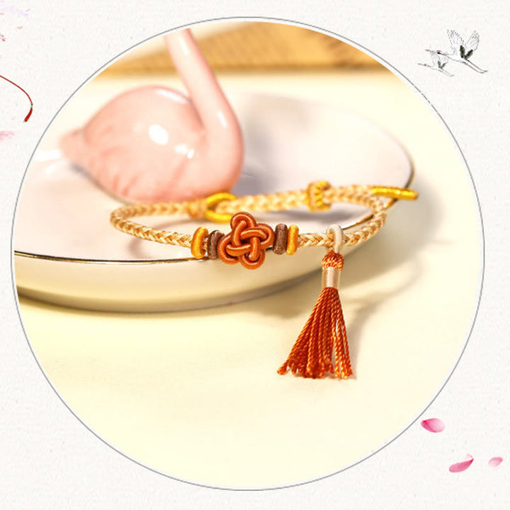 Bracelet de protection avec pompons et nœuds en fleurs de pêcher et Buddha Stones colorées