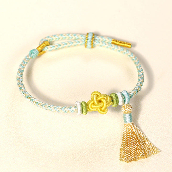 Bracelet de protection avec pompons et nœuds en fleurs de pêcher et Buddha Stones colorées