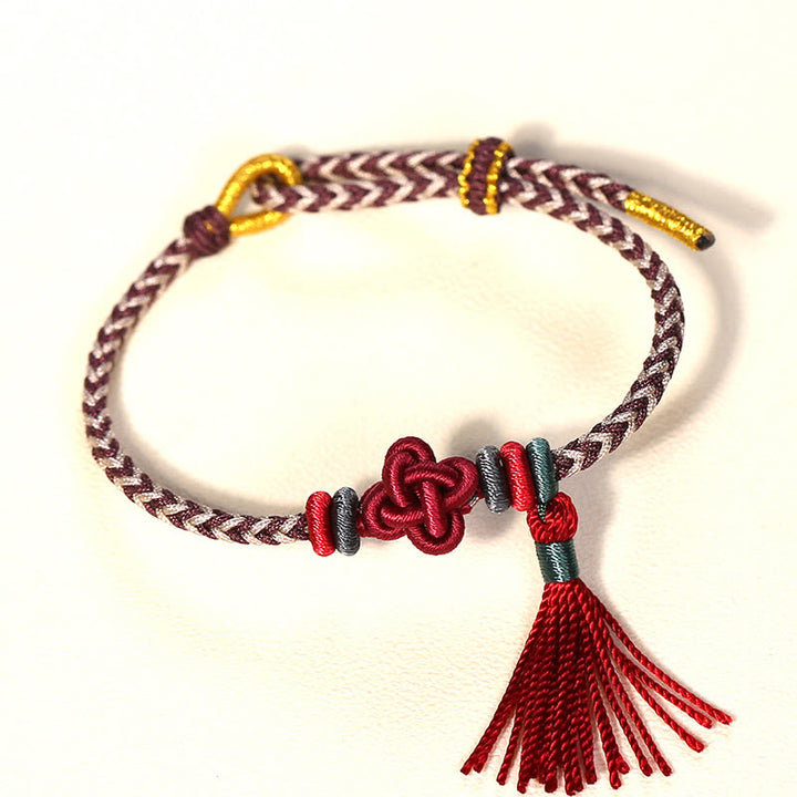 Bracelet de protection avec pompons et nœuds en fleurs de pêcher et Buddha Stones colorées