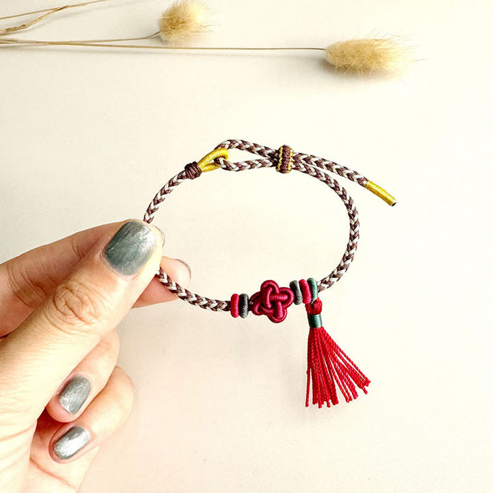 Bracelet de protection avec pompons et nœuds en fleurs de pêcher et Buddha Stones colorées