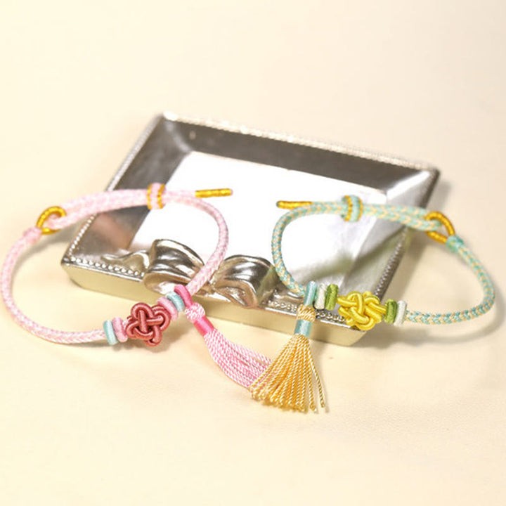 Bracelet de protection avec pompons et nœuds en fleurs de pêcher et Buddha Stones colorées