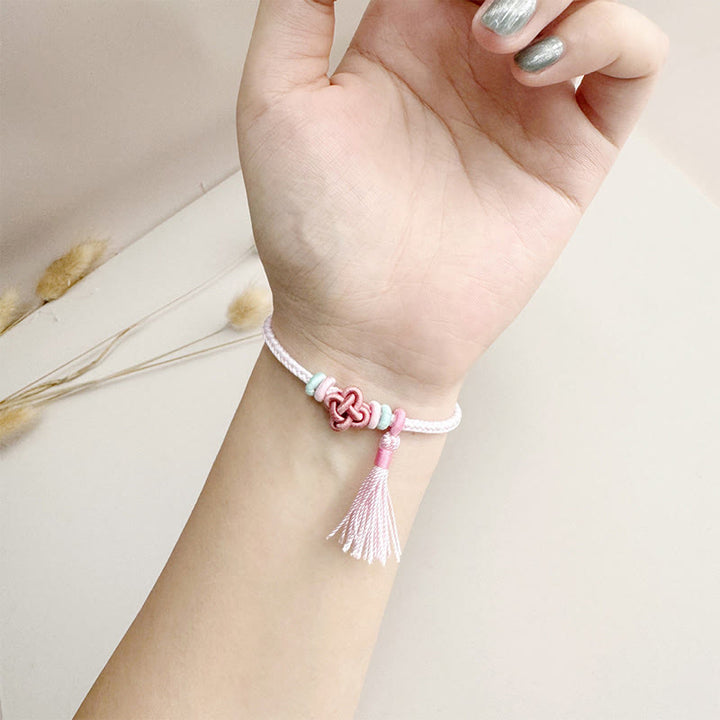 Bracelet de protection avec pompons et nœuds en fleurs de pêcher et Buddha Stones colorées