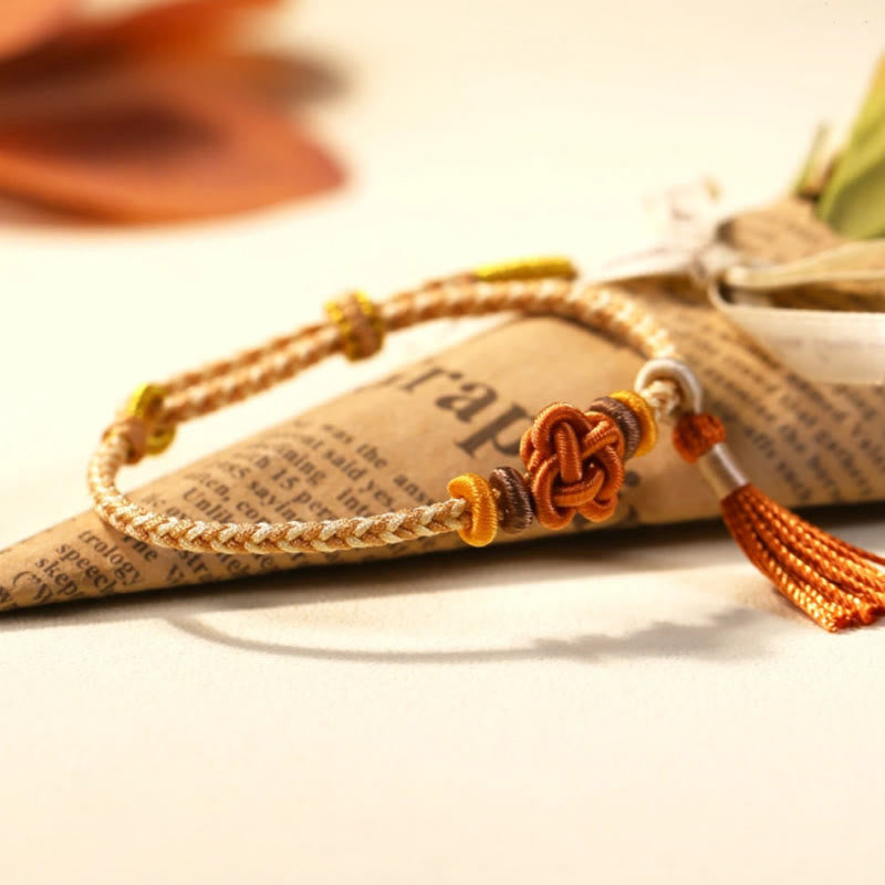 Bracelet de protection avec pompons et nœuds en fleurs de pêcher et Buddha Stones colorées