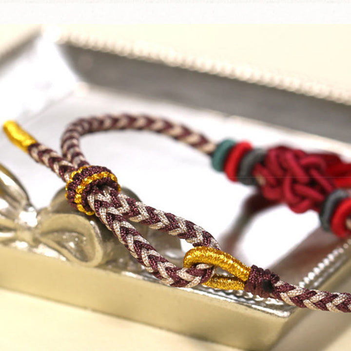 Bracelet de protection avec pompons et nœuds en fleurs de pêcher et Buddha Stones colorées