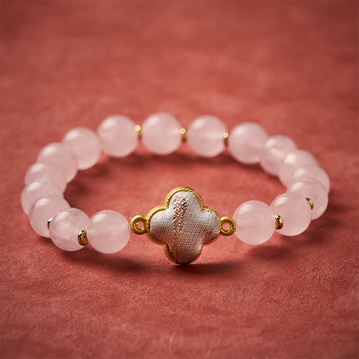 Buddha Stones Bracelet à breloques fait main en brocart de quartz rose avec trèfle à quatre feuilles et symbole de bénédiction - Quartz rose (même teinte – motif variable) - image 0