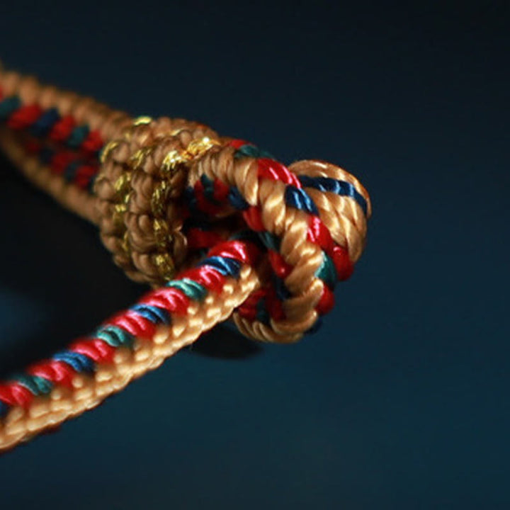 Bracelet de protection tressé à huit fils en Buddha Stones tibétain fait à la main avec roue de prière et nœud de paix