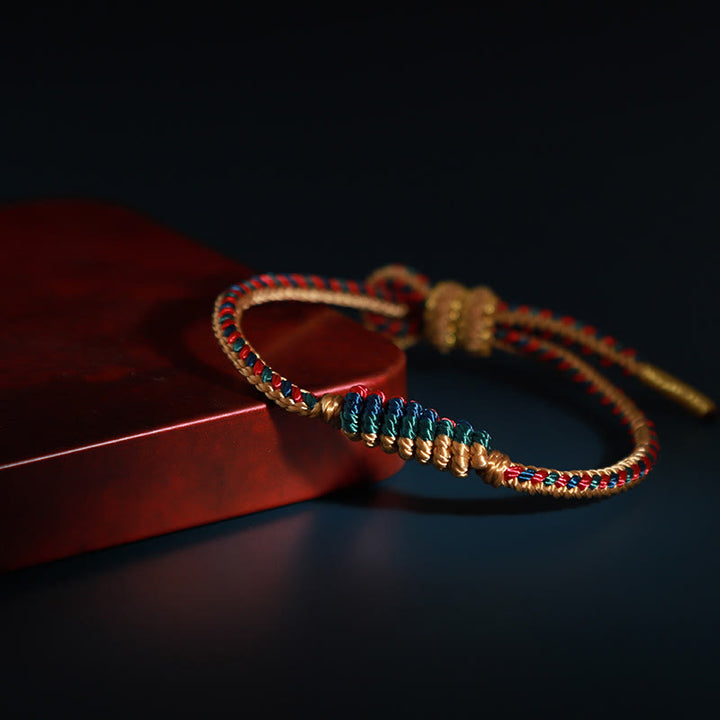 Bracelet de protection tressé à huit fils en Buddha Stones tibétain fait à la main avec roue de prière et nœud de paix