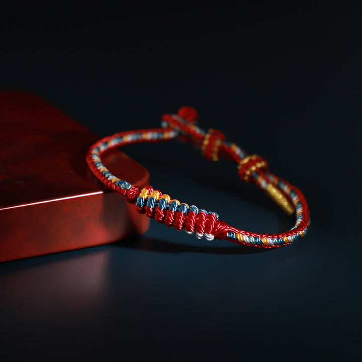 Bracelet de protection tressé à huit fils en Buddha Stones tibétain fait à la main avec roue de prière et nœud de paix